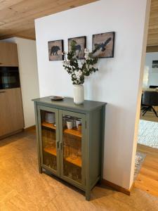 a green cabinet with a vase of flowers on it at Chalet Schneelöwe in Bettelried