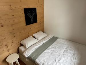 a small bedroom with a bed and a stool at Chalet Schneelöwe in Bettelried +3 photos