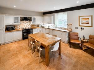 Una gran cocina con una mesa y sillas de madera. en 4 Murton Whitehouse Steading, en East Ord