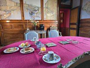 a table with plates of food on a purple table cloth at château de La Colinière - vue sur parc in Champtoceaux