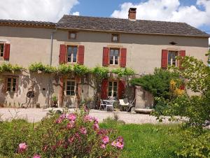 an old house with red shuttered windows and flowers at Maison d'hôtes la Passemarié in Andouque