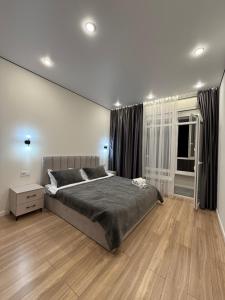 Un dormitorio con una cama grande y suelo de madera. en ESTET Comfort, en Almaty