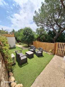 ein Hinterhof mit Stühlen, Gras und einem Zaun in der Unterkunft Le Cottage De Zénitude in Béziers