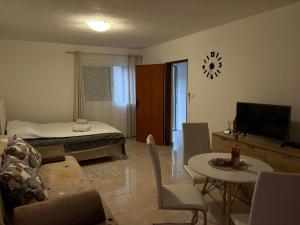 ein Wohnzimmer mit einem Bett, einem Tisch und einem Fernseher in der Unterkunft Apartman Strahinja in Tivat
