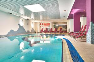 a pool in a hotel with red chairs and a pool at Zur Post Wellness und Sporthotel in Tännesberg
