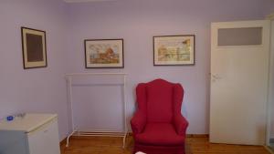 a red chair in a room with pictures on the wall at Philoxenia in Spata