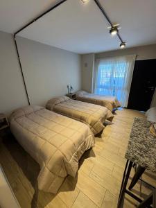 four beds lined up in a room with a window at Monoambiente Espacio super funcional in Guaymallen