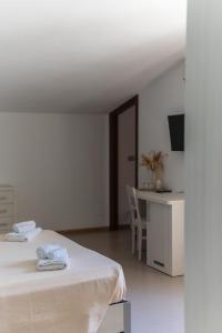 a white room with a bed and a desk at Hotel Maluentu in Putzu Idu