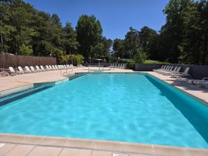 a large blue swimming pool with chairs and trees at Mobil-Home à Camiers dans un camping 3 étoiles in Camiers
