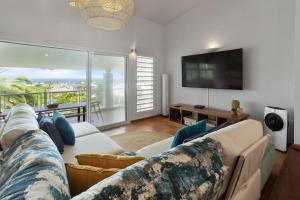 a living room with a couch and a flat screen tv at Villa Maravistah in Saint-François