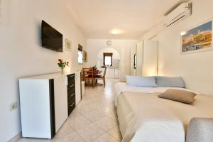 a bedroom with two beds and a tv on the wall at Apartments Pilic in Rošini