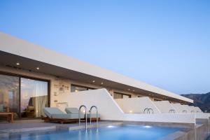 a hotel with a swimming pool in front of a building at Mouria Luxury Suites - Adults Only in Falasarna