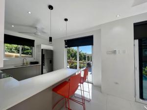 a kitchen with white counters and red chairs at The Indianna Luxury Pool & Spa in Whitehouse