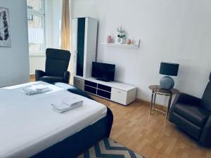 a hotel room with a bed and two chairs and a tv at Siegener Balkon-Refugium in Plauen