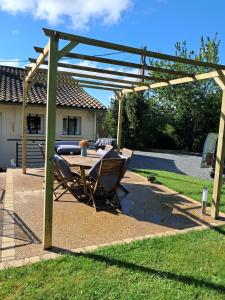 un patio avec une table et des chaises sous une pergola dans l'établissement Au doux rêve, à Puyfebert