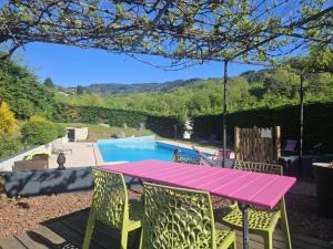 a pink table and chairs on a patio with a swimming pool at Logis Hôtel Restaurant L'Escapade in Le Crestet
