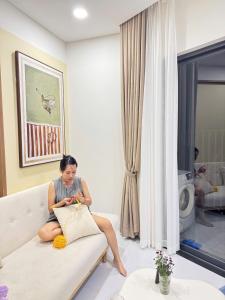 a woman sitting on a couch in a living room at Dori House Honas in Dĩ An +17 photos