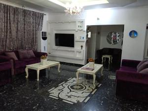 a living room with purple couches and a tv at Lavender Hotel and Spa in Mama