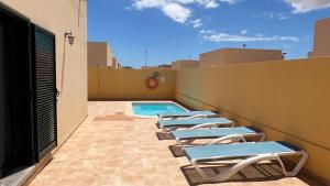 a row of chaise lounge chairs sitting on a roof at Anahi Homes Corralejo- Bicacarera 7 in La Oliva