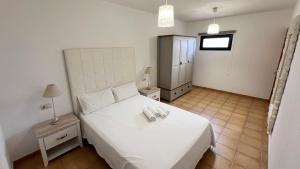 a bedroom with a white bed with two phones on it at Anahi Homes Corralejo- Bicacarera 7 in La Oliva +7 photos