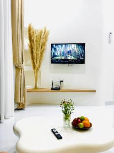 a living room with a television and a bowl of fruit on a table at Dori House Honas in Dĩ An