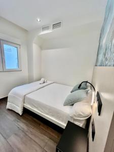 a white bedroom with a bed and a window at Rooms&Go in Alicante