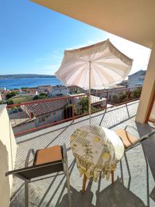 a balcony with a table and an umbrella and chairs at Apartmani Lili in Crikvenica
