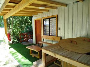 a porch of a cabin with a wooden table and bench at cabañas mañio melipeuco in Melipeuco