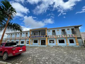 a building with a red car parked in front of it at Hotel Acqua Park in Capim Grosso