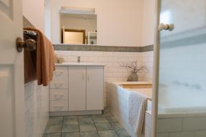 a white bathroom with a sink and a mirror at Cool beachside apartment on Jetty Road Brighton in Brighton +13 photos