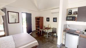 a room with a bed and a table and a kitchen at La Case des Caraïbes in Le Gosier