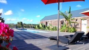 a patio with two chairs and an umbrella next to a pool at La Case des Caraïbes in Le Gosier +6 photos
