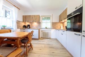 a kitchen with white cabinets and a wooden table at Alpspitzstubn - Ihr Wohlfühlort mit Bergpanorama in Grainau