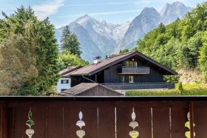 a house with a fence and mountains in the background at Alpspitzstubn - Ihr Wohlfühlort mit Bergpanorama in Grainau