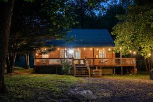 a wooden house with a deck at night at Secluded Creekside Cabin Hot Tub and Fire Pit in Cosby
