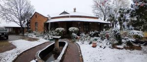 a house with a snow covered yard with a building at Sandstone Escape Guesthouse in Ladybrand