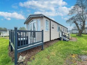 洛斯托夫特Homely Caravan With Decking And Wifi In Lowestoft Ref 12097B的移动房屋设有门廊和围栏