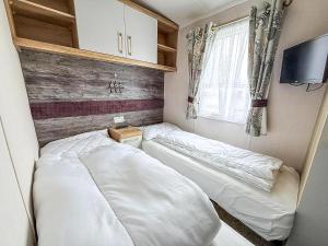 洛斯托夫特Homely Caravan With Decking And Wifi In Lowestoft Ref 12097B的一间小卧室,内配两张床