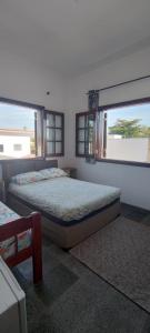 Un dormitorio con una cama y dos ventanas. en Arandu, en Peruíbe 28 fotos más