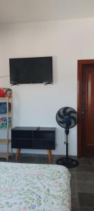 Un dormitorio con un televisor de pantalla plana en una pared. en Arandu, en Peruíbe