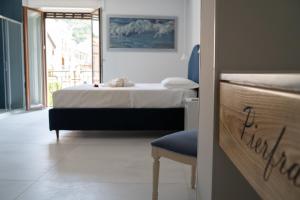 a bedroom with a bed and a chair and a window at B&B PierGaia in Santa Maria di Castellabate