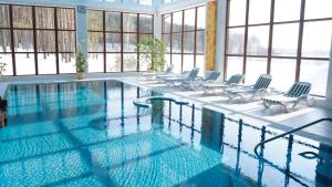 a large swimming pool with chairs and windows at Park Hotel Borvikha in Pilichki