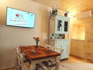 Un comedor con una mesa y un televisor en la pared. en Arcaica Cummersa - Dimora in pietra, en Alberobello
