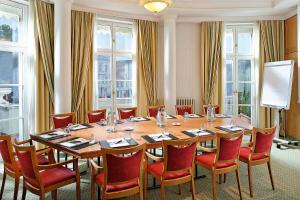 una sala de conferencias con una gran mesa de madera y sillas en Hotel Am Jägertor en Potsdam