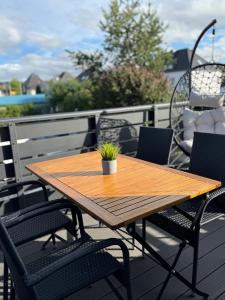 a wooden table on a deck with chairs and a plant at ZwoLu Apartments in Bornheim +29 photos