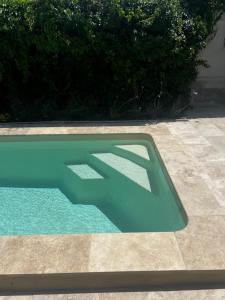 a blue swimming pool with a shadow on the ground at Maison Pamplemousse in Arles