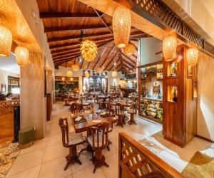 a restaurant with wooden tables and chairs and chandeliers at Hotel & Spa Poco a Poco - Costa Rica in Monteverde Costa Rica