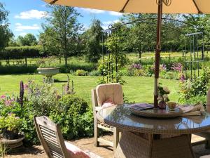 a patio table with an umbrella in a garden at Oak Lodge in Moreton Pinkney