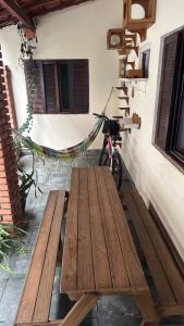 Una bicicleta estacionada junto a un banco de madera al lado de un edificio. en Pousada Flores do Campo Ita, en Itanhaém