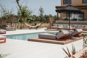 ハニア・タウンにあるVilla Agali I "Free" heated pool & 70m to Sea!のラウンジチェアとパラソル付きのプール、